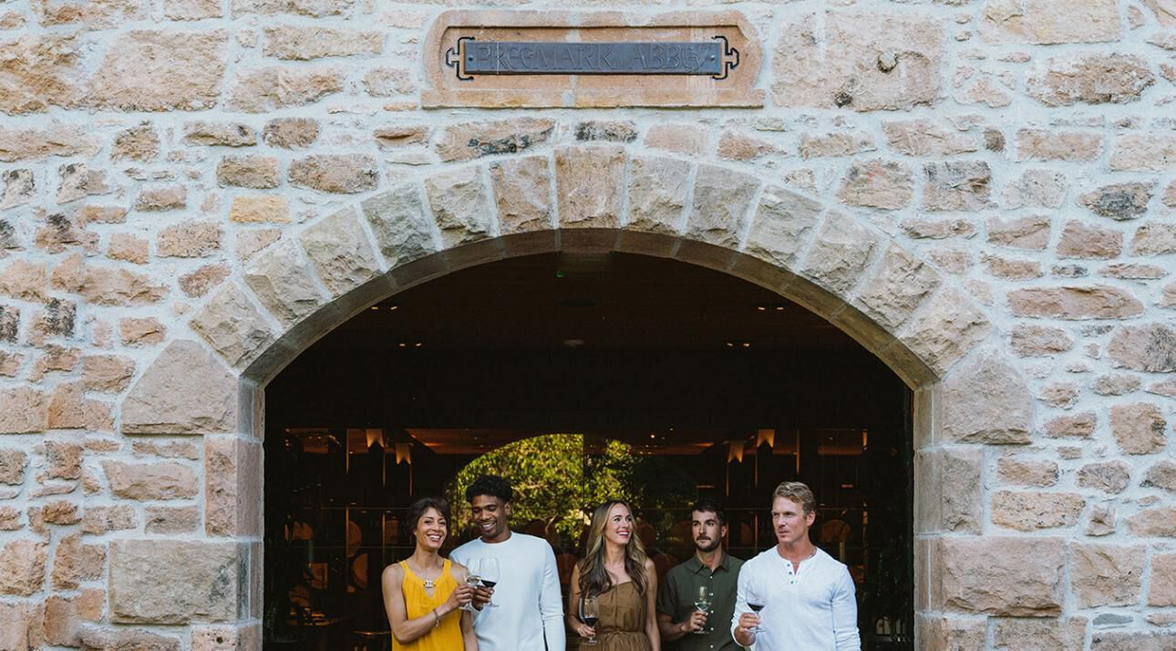 A group of people standing under a brick archway at Freemark Abbey Estate